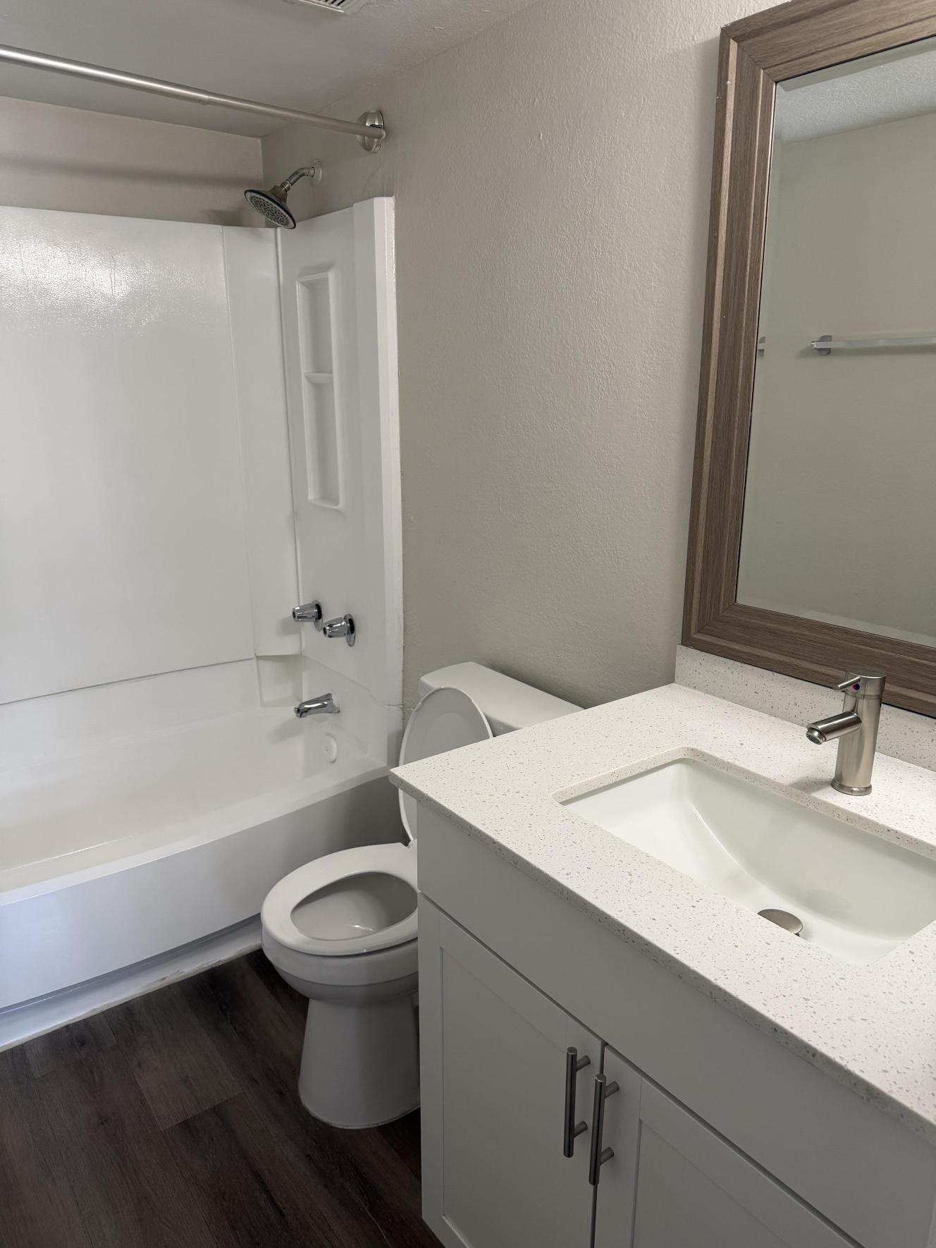 Baño con tina, tocador y espejo enmarcado